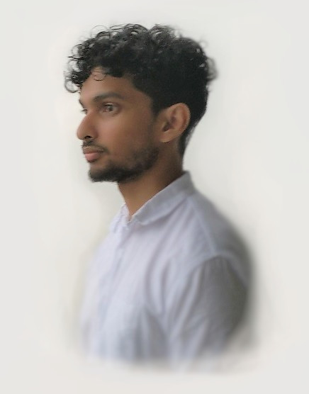 Nim wearing a white shirt, with curly hair and a light beard.